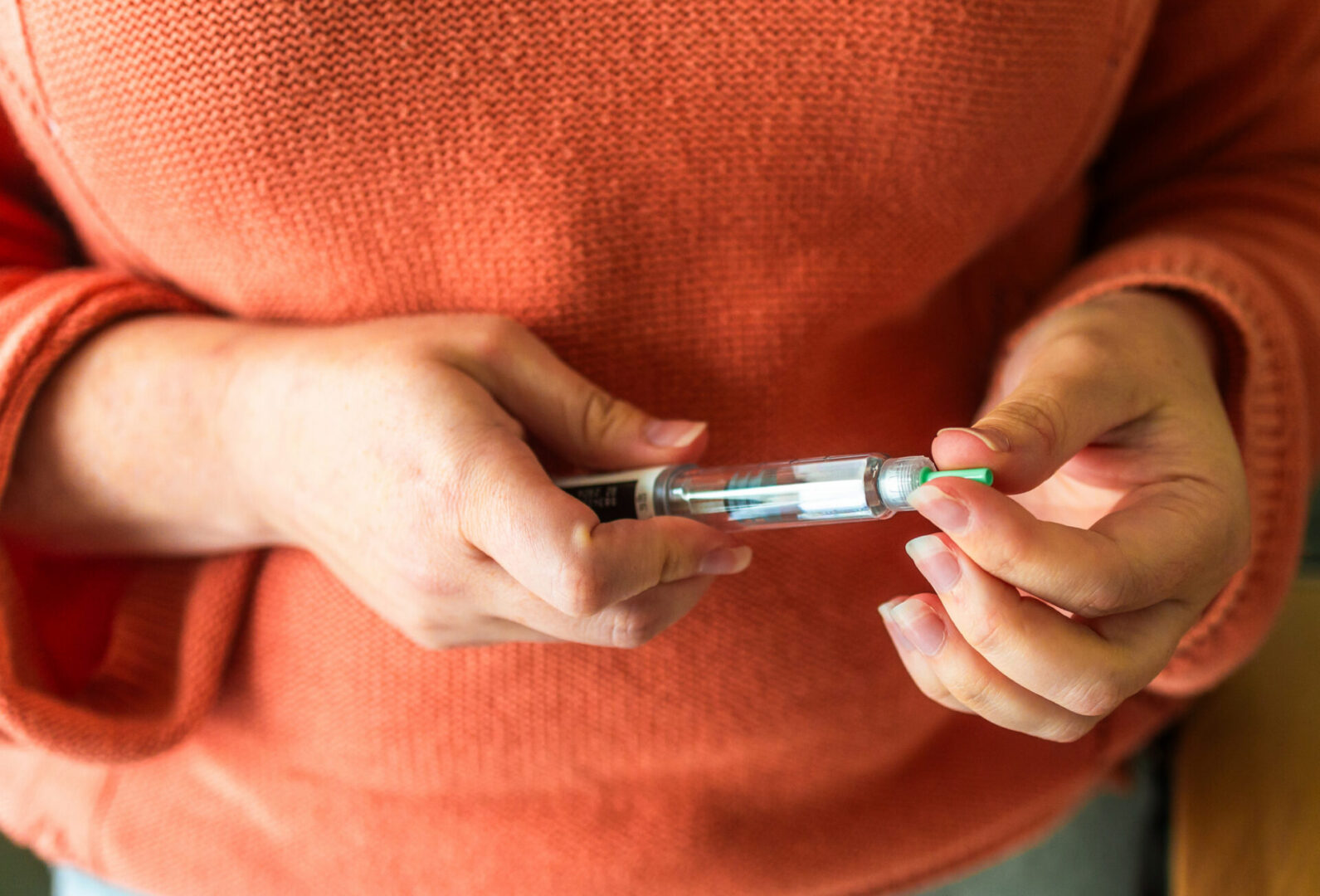 Hands preparing insulin pen for injection