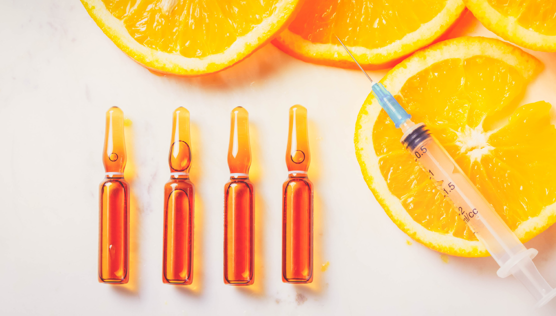 Vitamin C vials, syringe, and orange slices