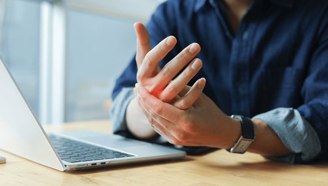 Person experiencing wrist pain at desk